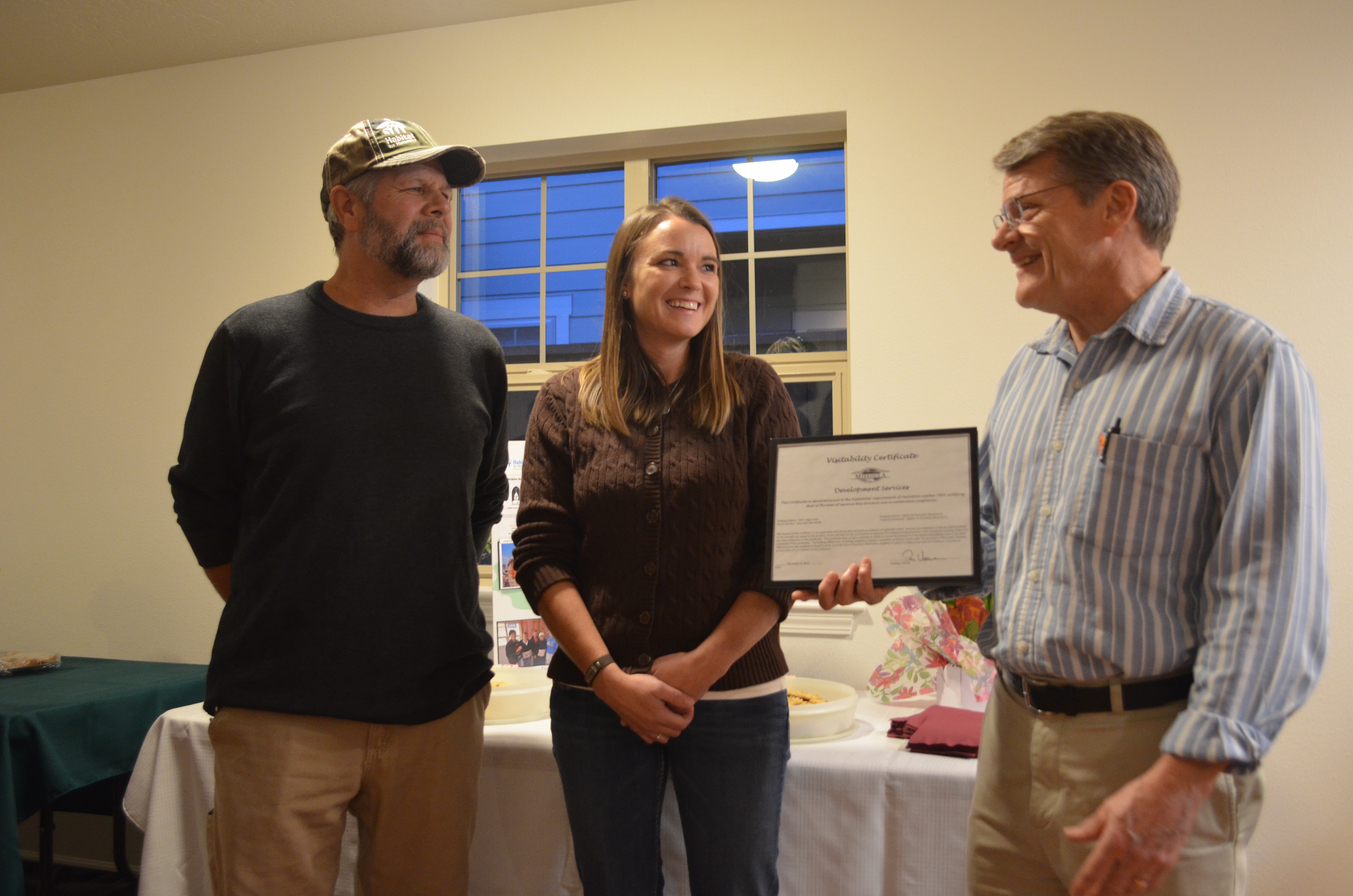 City employee Don Verrue presents the award to the build team leader and the new home owner.